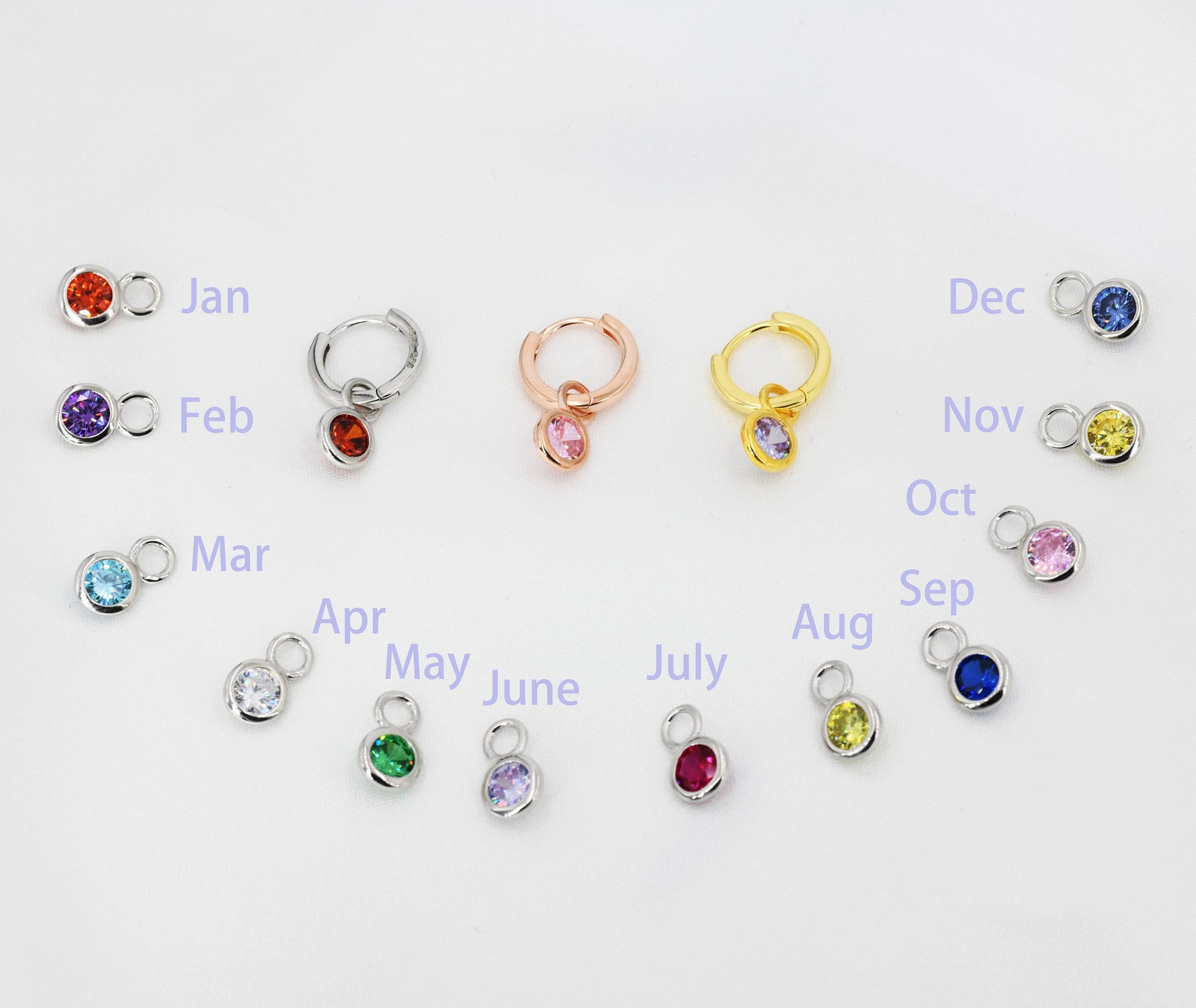 A complete 12-month birthstone charm collection in 925 Sterling Silver, featuring three different huggie hoop finishes in silver, gold, and rose gold to showcase personalized birthday gifting options.