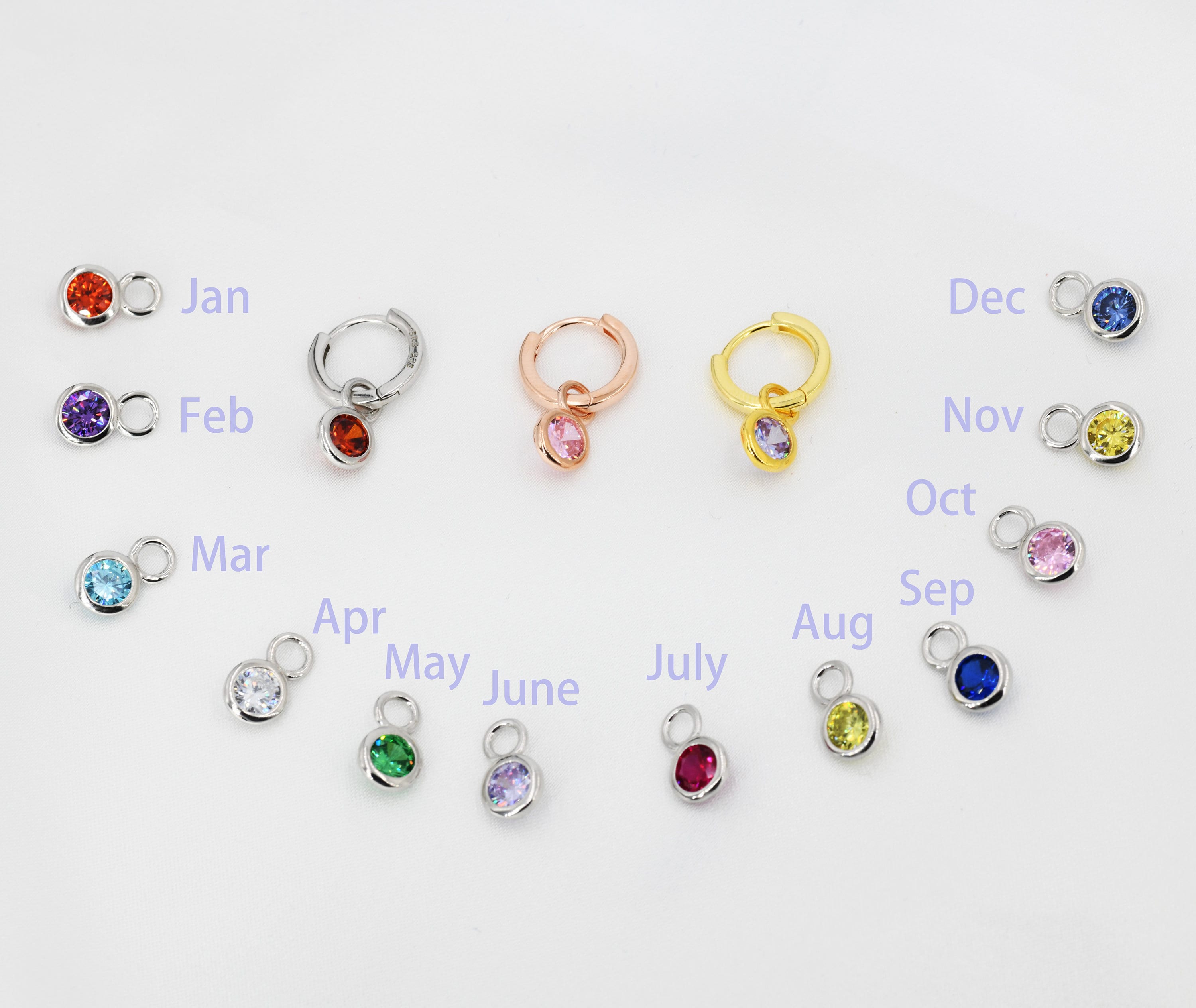 A complete 12-month birthstone charm collection in 925 Sterling Silver, featuring three different huggie hoop finishes in silver, gold, and rose gold to showcase personalized birthday gifting options.