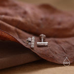 May include: A pair of silver bar earrings with small diamonds set into the bars. The earrings are on a brown background.