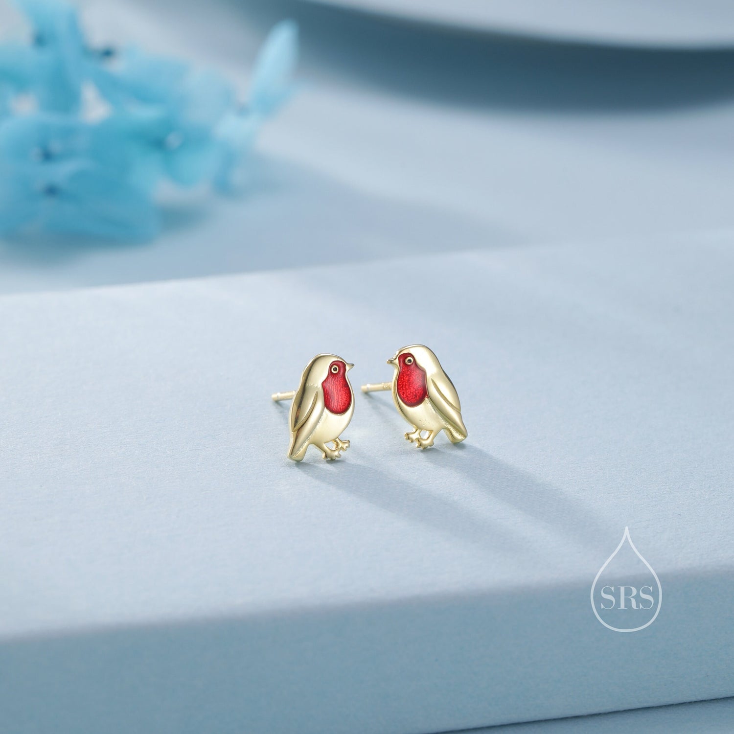 May include: A pair of gold-tone earrings featuring a red-breasted robin design. The robins are detailed with white and gold accents.