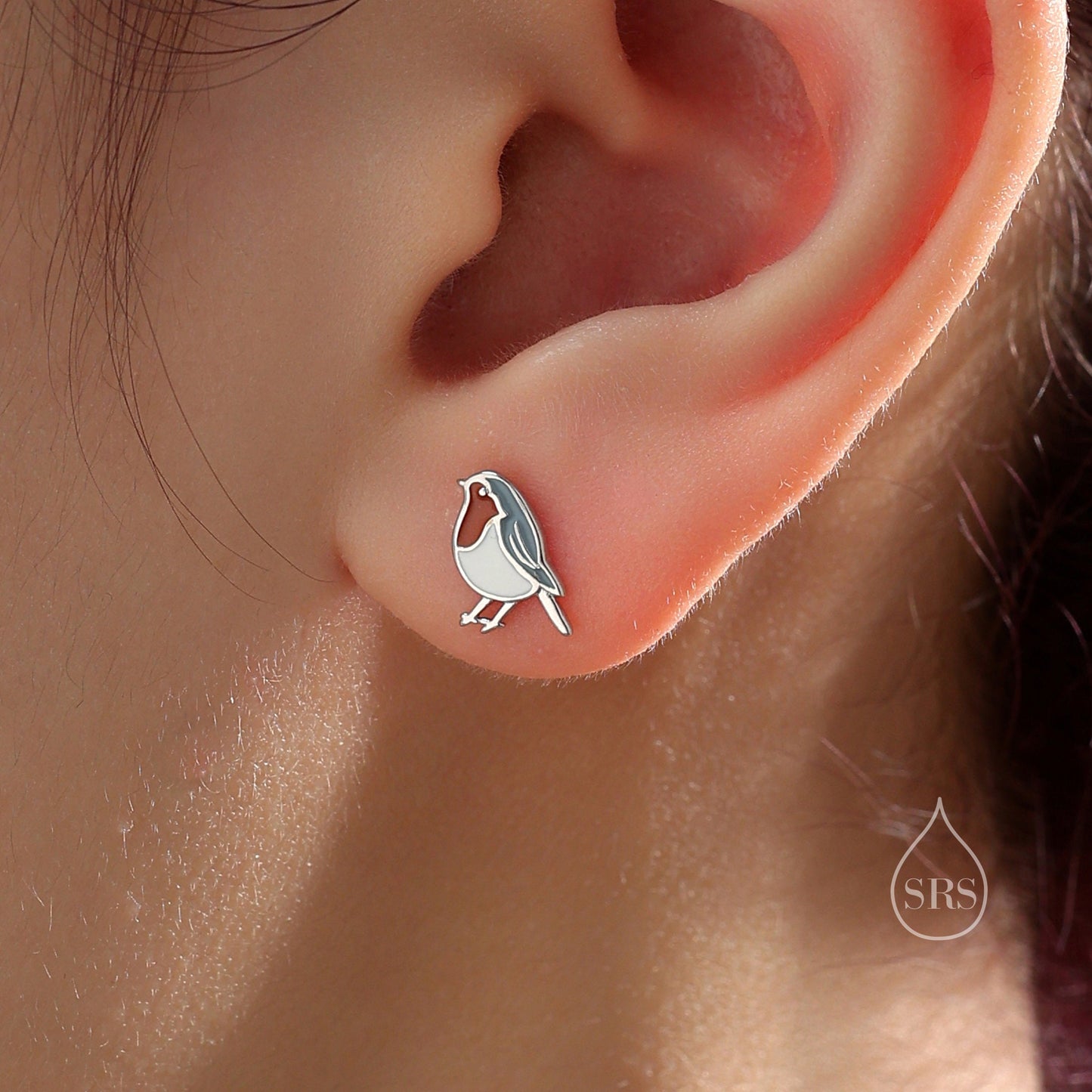 May include: Silver stud earrings featuring a small, white robin bird design.