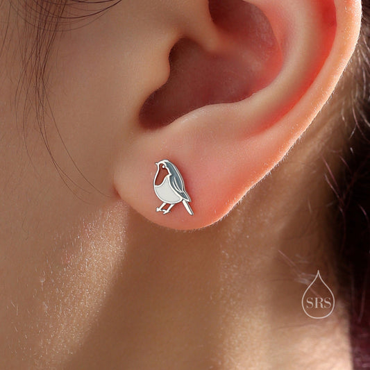 May include: Silver stud earrings featuring a small, white robin bird design.