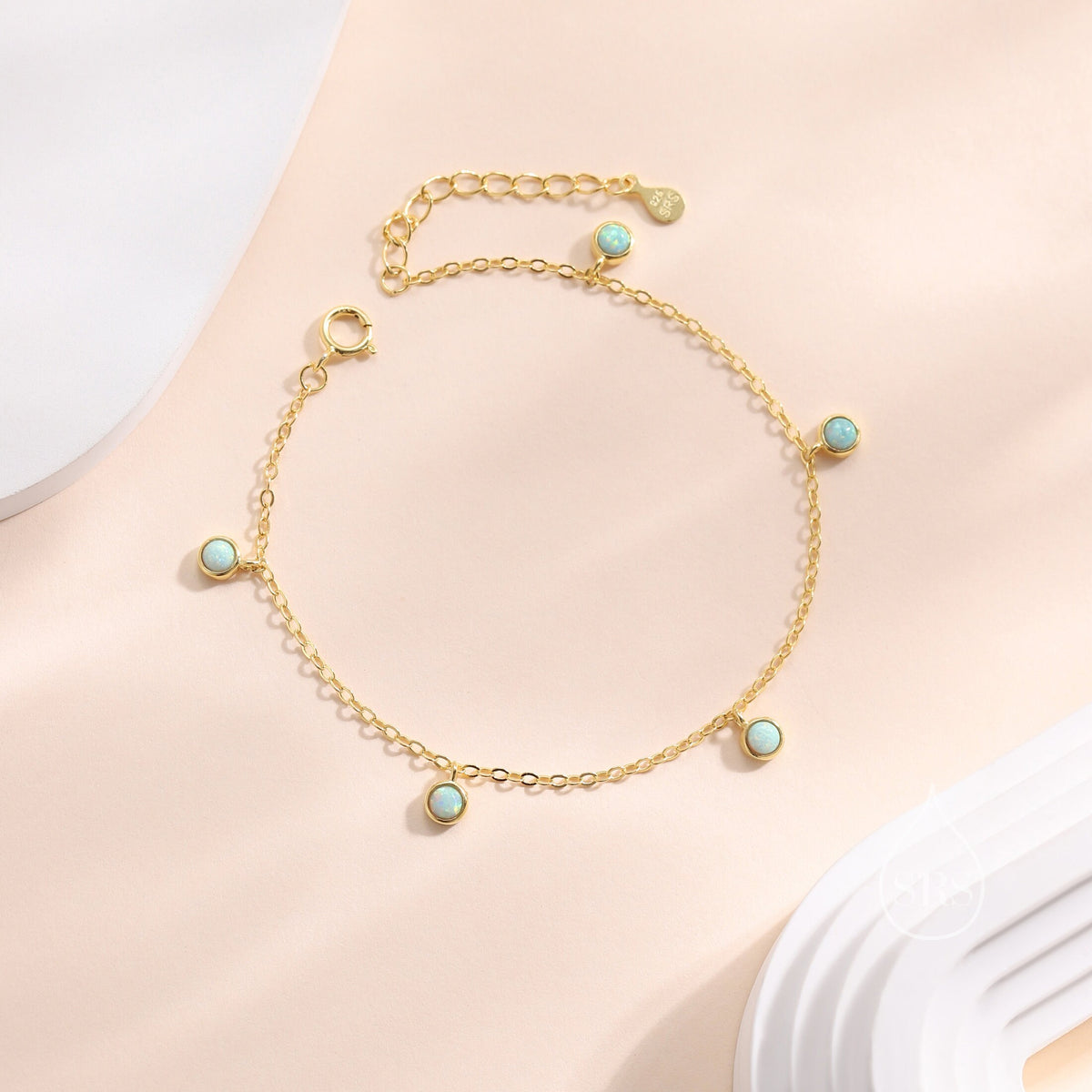 May include: A gold chain bracelet with five small round blue opal stones. The bracelet has a lobster clasp closure.