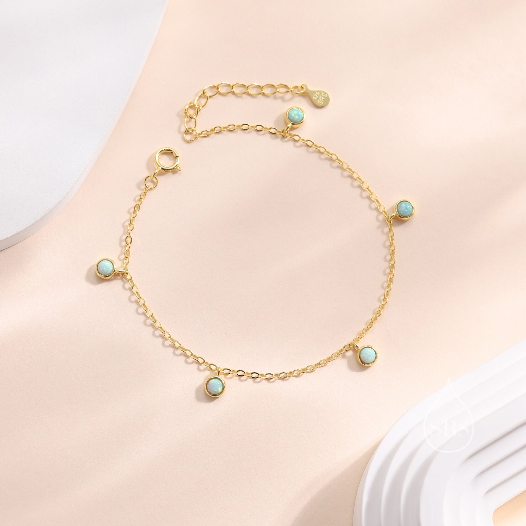 May include: A gold chain bracelet with five small round blue opal stones. The bracelet has a lobster clasp closure.