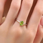 May include: A silver ring featuring a green oval gemstone. The ring is worn on a person&