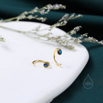 May include: A pair of gold hoop earrings with a teardrop-shaped blue gemstone on each hoop.